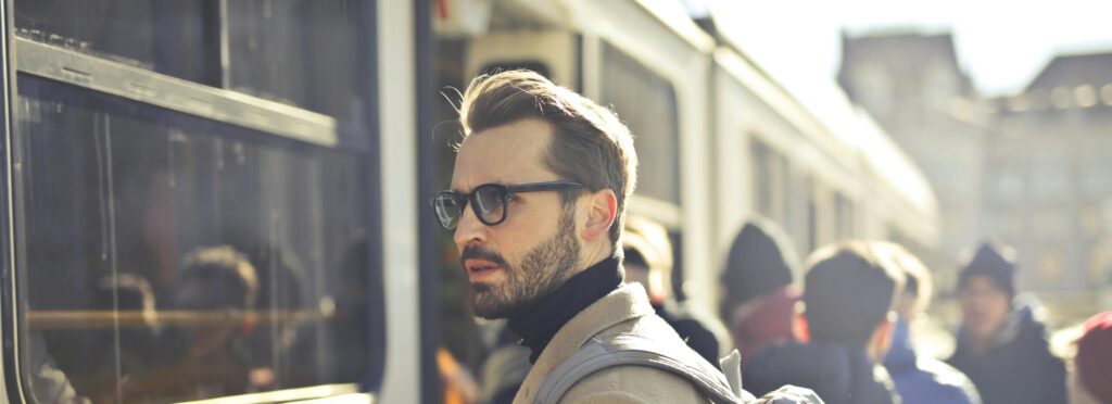 A stylish man with a backpack boards a tram in bustling Budapest, Hungary, during the day.